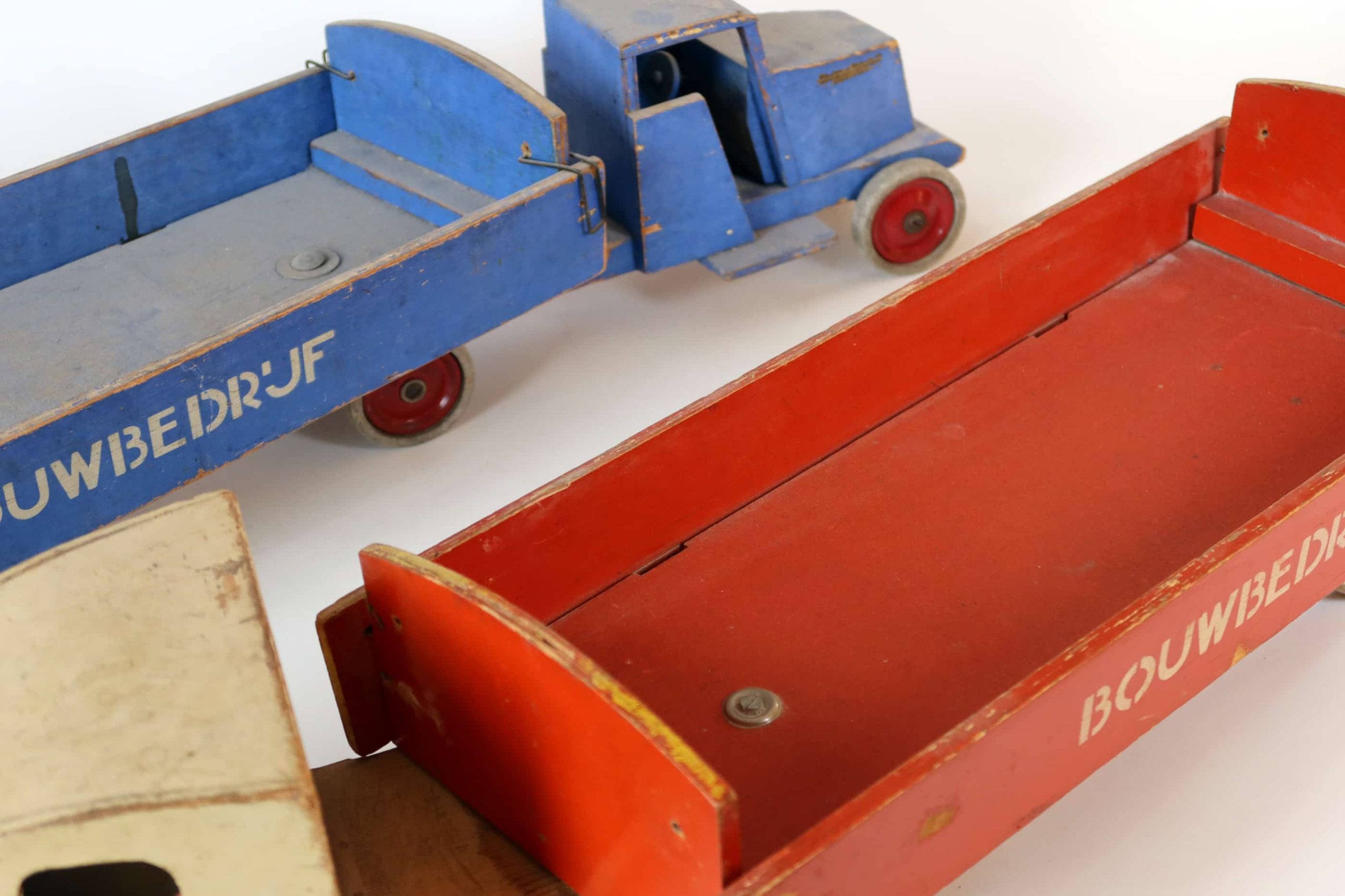 Speelgoedvrachtwagens van Ko Verzuu met het opschrift Bouwbedrijf, een in blauw en geel, de ander in rood en crème 